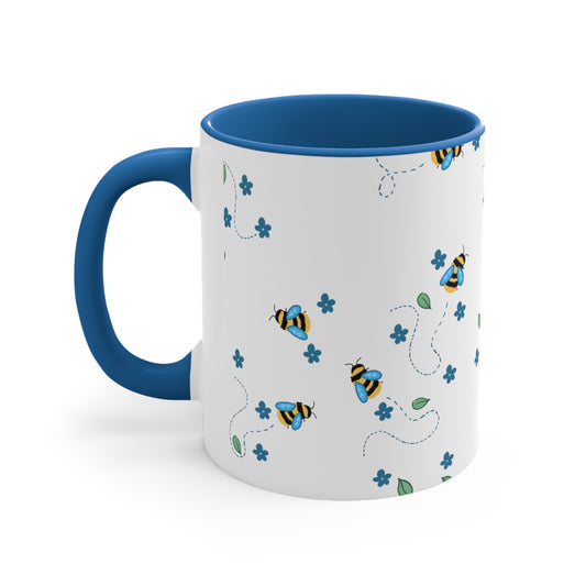 Cartoon bees With broken line trails behind them, Dark blue flowers, Loose green leaves In an all over pattern on top of a white background. The inside of the mug, and the handle is a medium dark blue color
