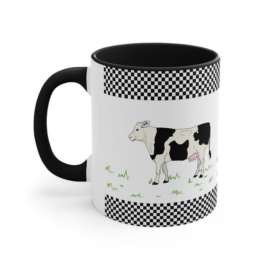 White mug with a cow and grass. The brim and the bottom of The mug has a design of Small black-and-white checkers. The inside of the mug, and the handle are black